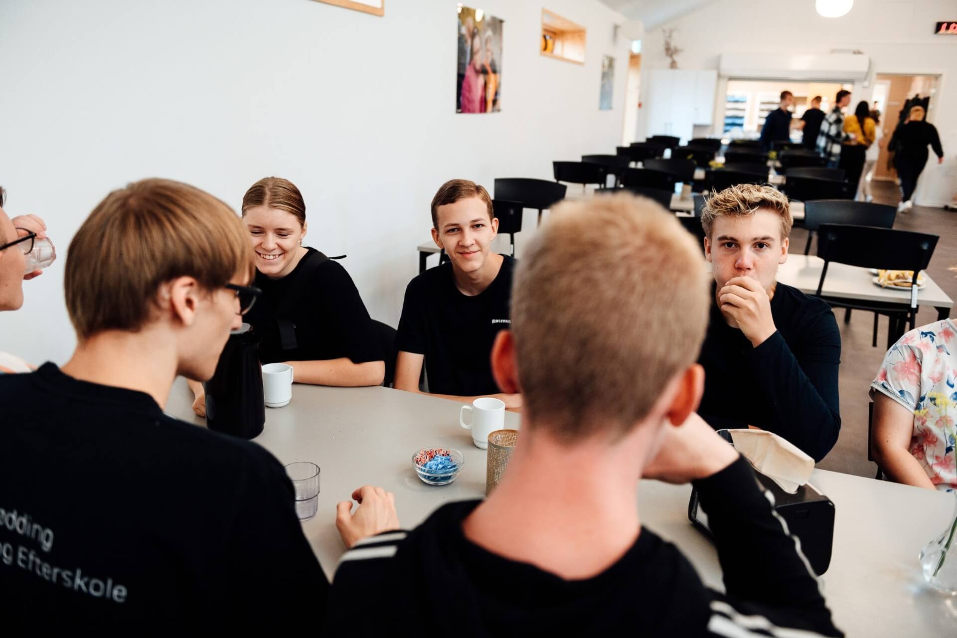 Elever ved bord i klasselokale med lærer tæt på